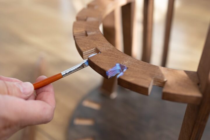 Ilustrační stock: dřevěné desky spojené lepidlem v dílenských svěrách, bílá lahev lepidla na pracovním stole, bez loga
