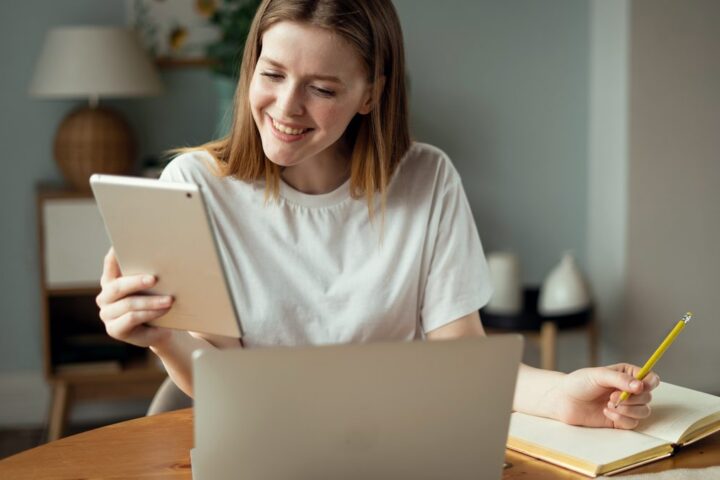 Žena s tabletem a notebookem plánuje rezervace kurzů