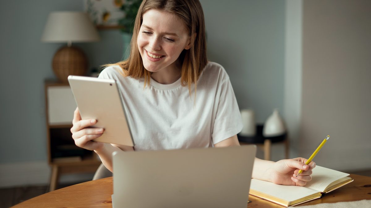 Žena s tabletem a notebookem plánuje rezervace kurzů