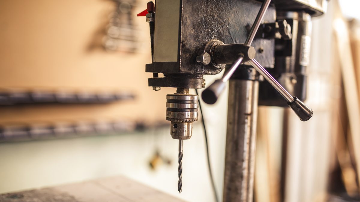 Ilustrační stock: stolní vrtačka s rotujícím vrtákem, bez rukavic, upnutý obrobek, čistá dílna, bez loga