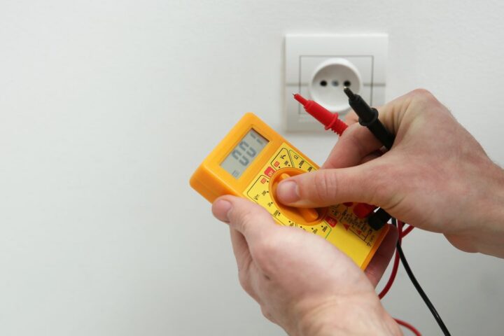 Ilustrační stock: elektrikář ověřuje zkoušečku napětí na živém zdroji před začátkem práce na elektrickém okruhu, civilně, bez loga či značek nářadí