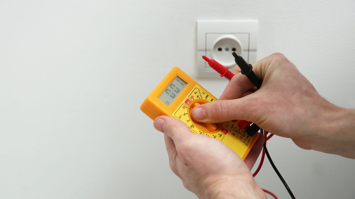 Ilustrační stock: elektrikář ověřuje zkoušečku napětí na živém zdroji před začátkem práce na elektrickém okruhu, civilně, bez loga či značek nářadí